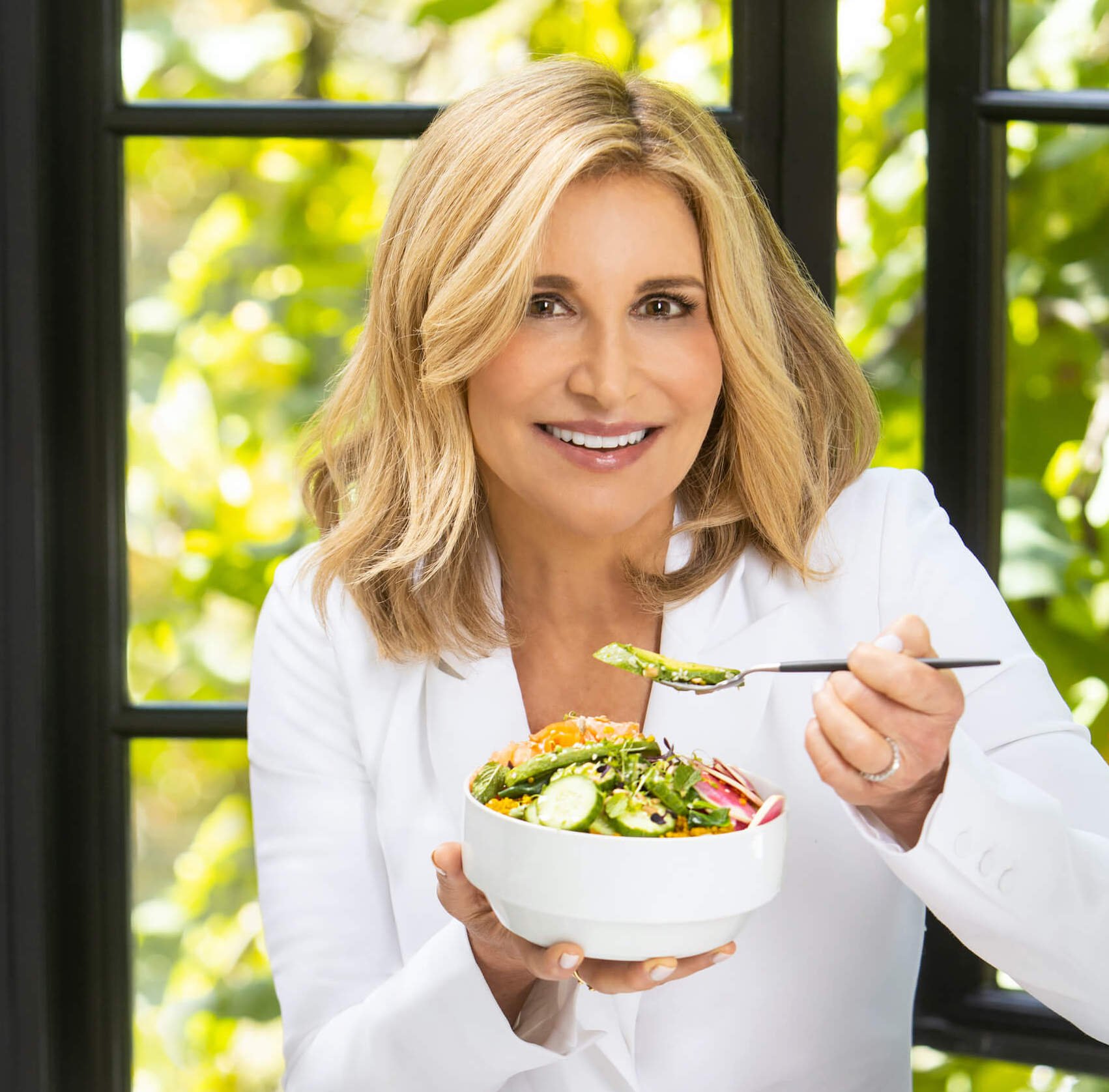 Woman smiling eating bowl of vegetables
